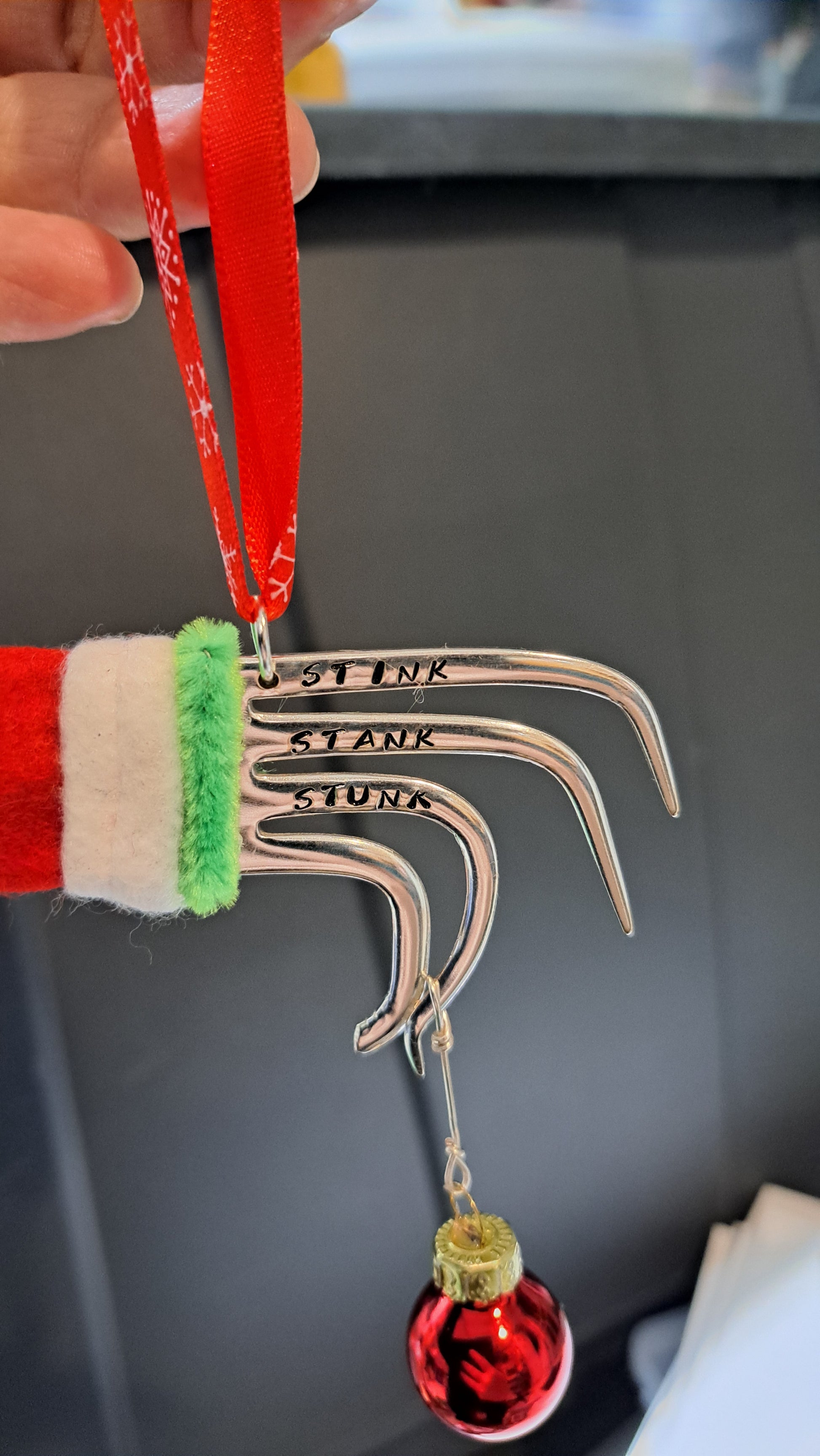 Handmade vintage silverware Christmas Ornament made from a fork shaped as the hand of the Grinch holding a Christmas bauble