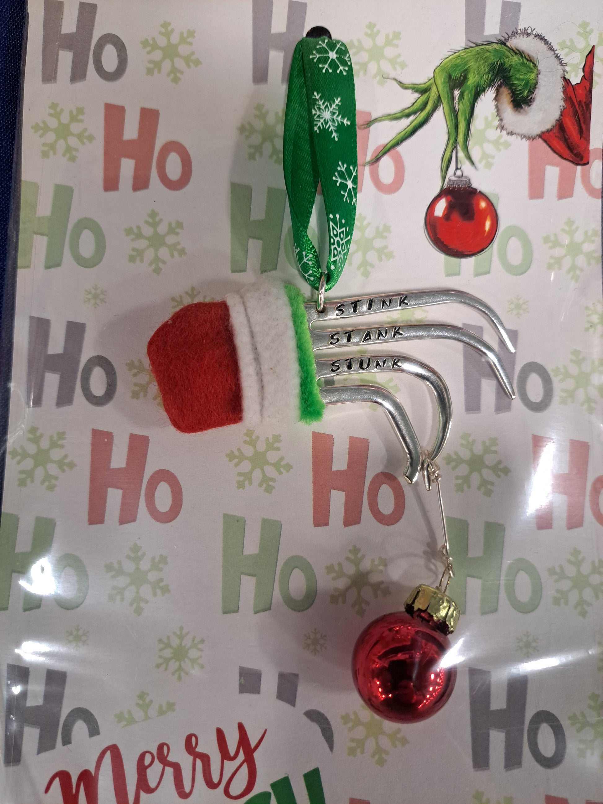 Handmade vintage silverware Christmas Ornament made from a fork shaped as the hand of the Grinch holding a Christmas bauble