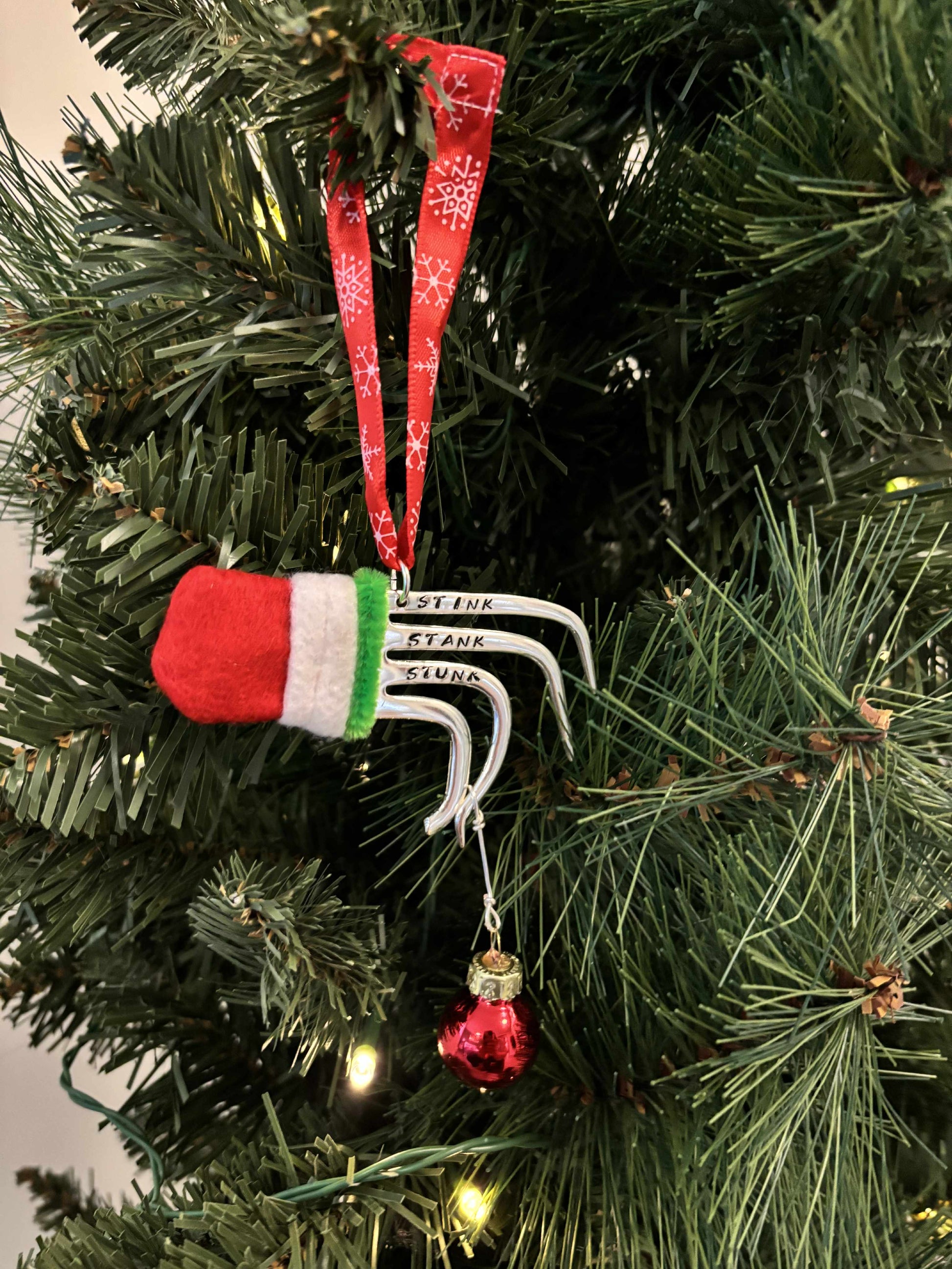 Handmade vintage silverware Christmas Ornament made from a fork shaped as the hand of the Grinch holding a Christmas bauble