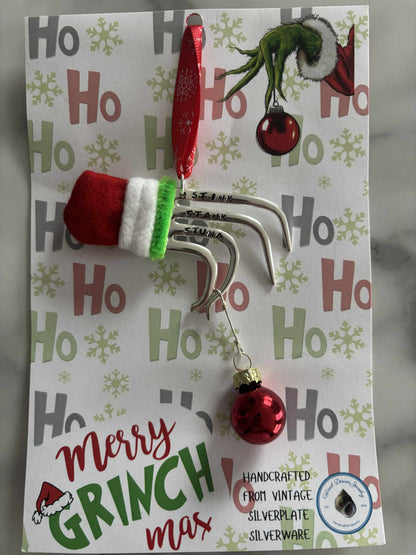 Handmade vintage silverware Christmas Ornament made from a fork shaped as the hand of the Grinch holding a Christmas bauble